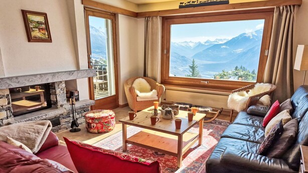 A cozy living room with a fireplace, a sofa, a chair, a coffee table, and a large window with a mountain view. - Wonderful private villa for 10 guests with WIFI, TV, terrace and panoramic view (Bluche)