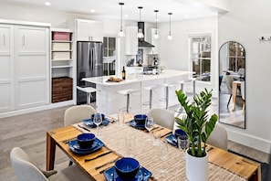 A modern kitchen with white cabinetry, a central island, and pendant lighting. - Smart TV | Murphy Bed | Near Back Cove | Parking (Portland)