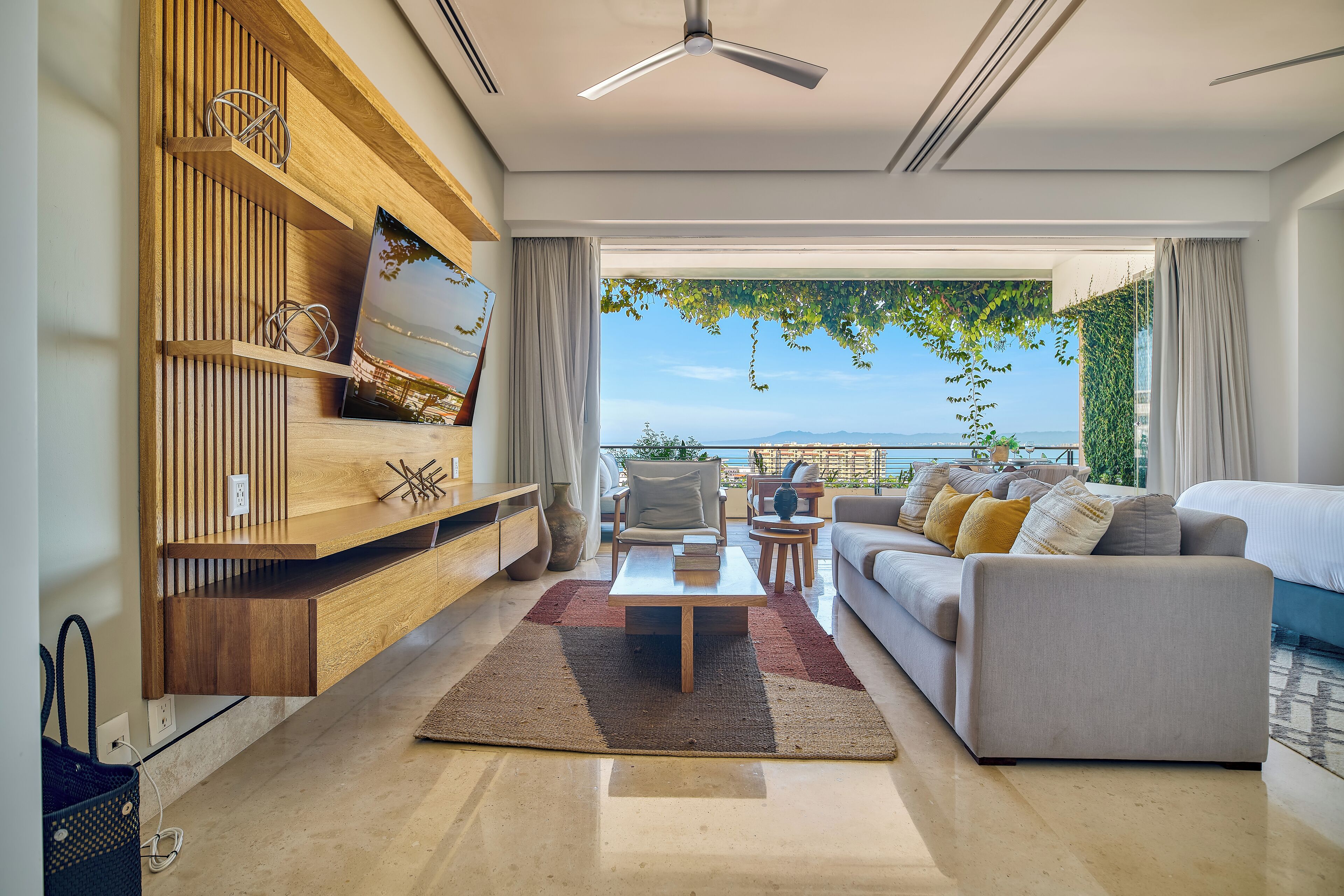 A modern living room with a sofa, coffee table, and TV on a wooden shelf.