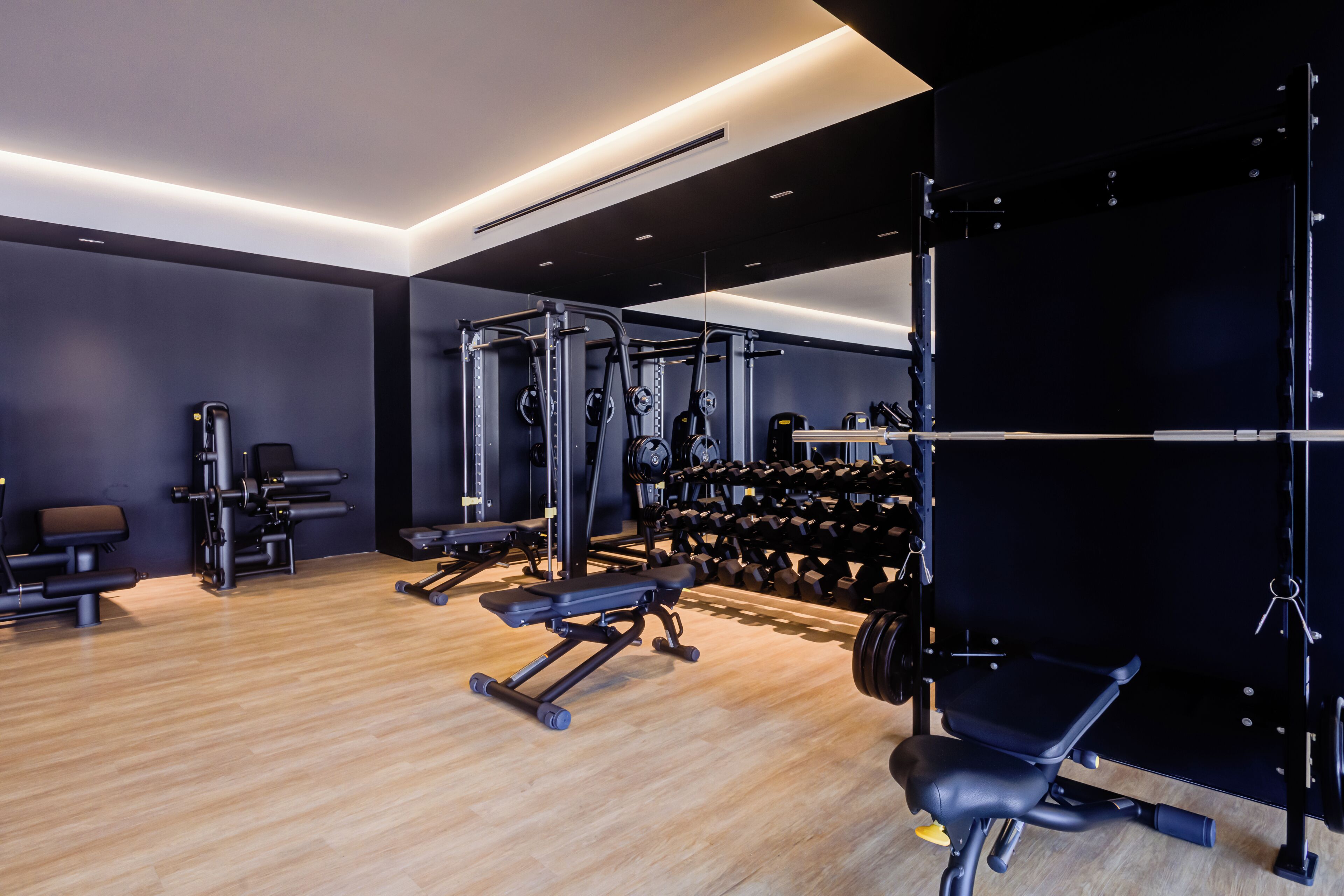 A modern gym with various exercise equipment, including weight machines, free weights, and a squat rack.