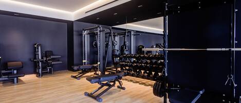 A modern gym with various exercise equipment, including weight machines, free weights, and a squat rack.