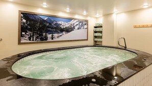 Ein Whirlpool mit einer Berglandschaftsmalerei, eine Holzablage mit Handtüchern und ein Holzgestell mit Haken.