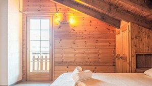 Ein gemütlicher Holzraum mit einem Bett, einer Tür und einem Fenster.