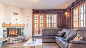 Ein gemütliches Wohnzimmer mit Kamin aus Stein, einer Ledersofa und einem Fliesenboden.