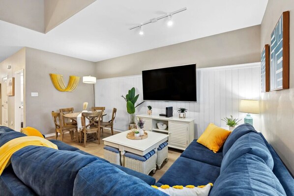 A modern living room with a sofa, a dining table, and a TV.