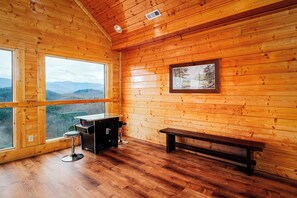 Une pièce de cabane en bois avec une grande fenêtre, un banc en bois et une petite table avec une chaise.