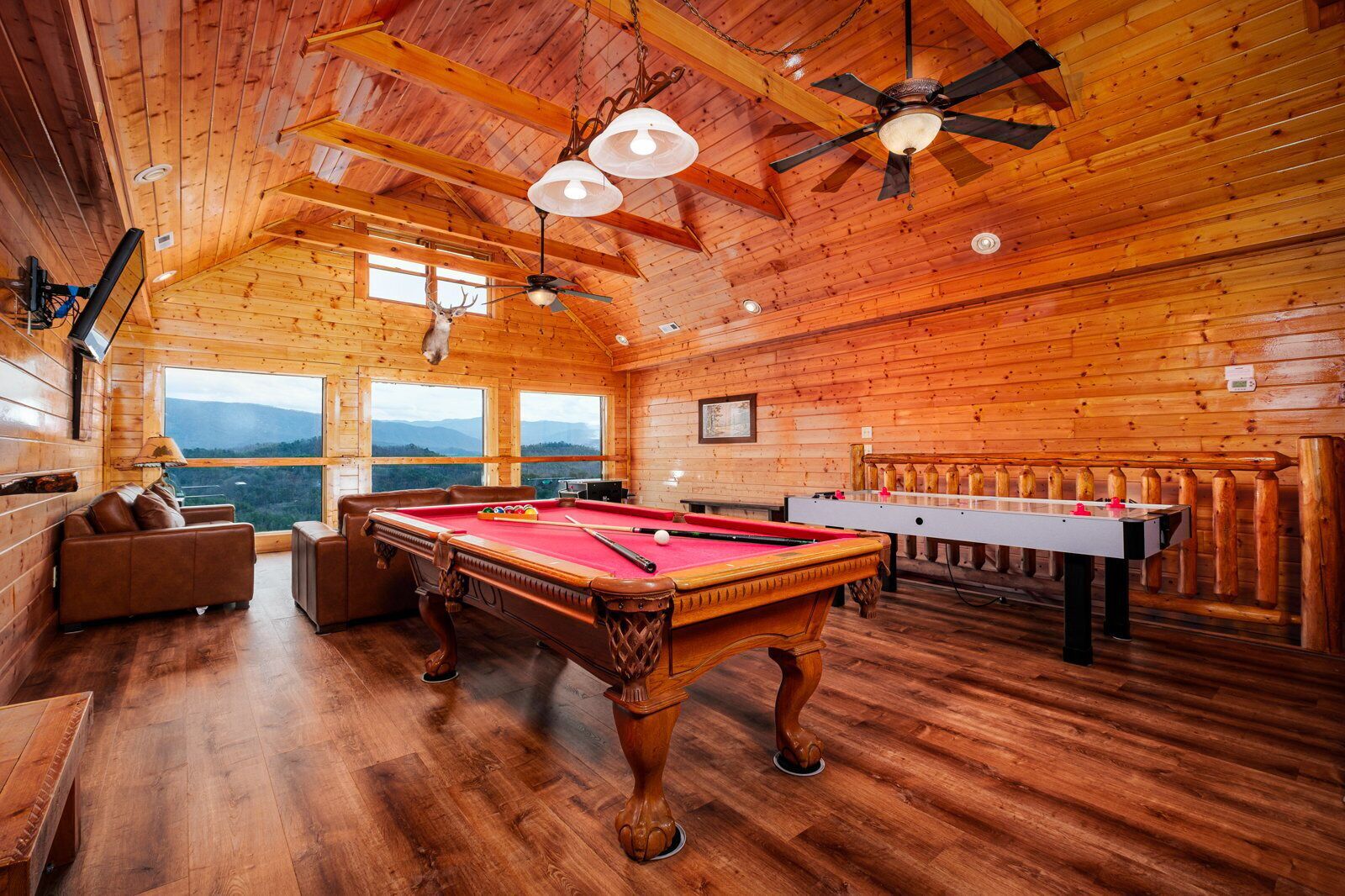 Uma cabana de madeira com mesa de bilhar, mesa de pebolim e um sofá.