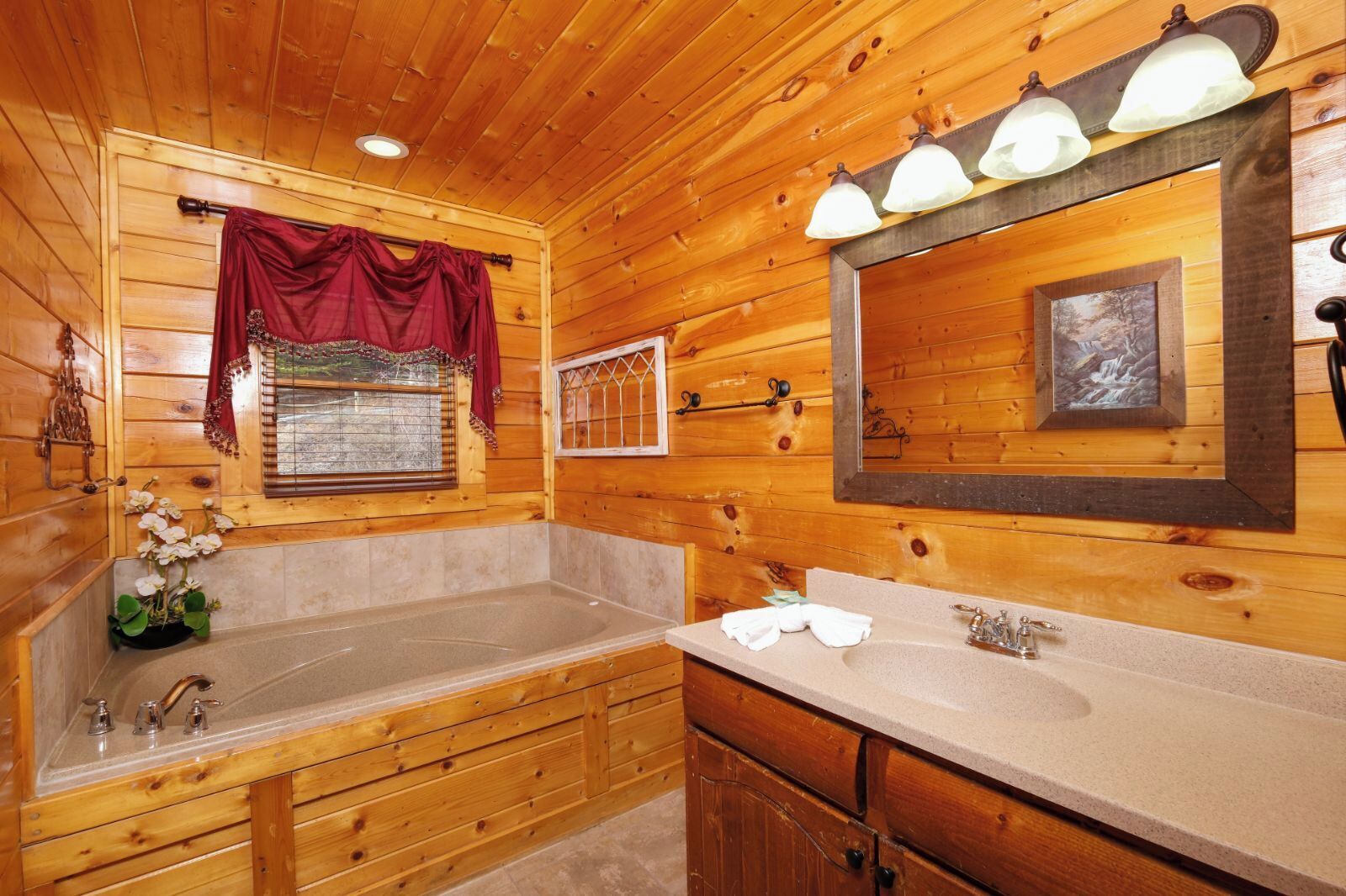 Un bagno in una baita di legno con una vasca da bagno ampia, un mobile lavabo con lavandino e uno specchio.