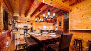 Een houten chalet van binnen, met een eethoek, keuken en bar.