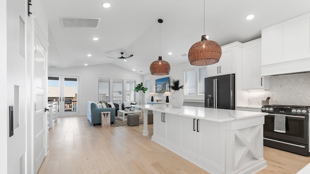 A modern kitchen with white cabinetry, a large island, and a black stove. - "Sea Ya at Holden" BRAND NEW 4 Bedroom, 4.5 Bath Home w/ PRIVATE POOL and Elevator! (Holden Beach)
