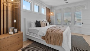 A bedroom with a bed, bedside table, and a ceiling fan. - "Sea Ya at Holden" BRAND NEW 4 Bedroom, 4.5 Bath Home w/ PRIVATE POOL and Elevator! (Holden Beach)