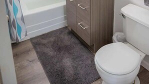 A bathroom with a bathtub, a sink, a toilet, and a shower. - WindanSea Ocean View (San Diego)