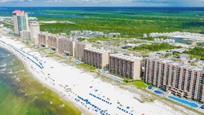 A beachfront hotel with multiple high-rise buildings, a sandy beach, and a clear view of the ocean.