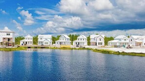 A waterfront residential area with multiple white houses, a clear blue sky, and a calm body of water.