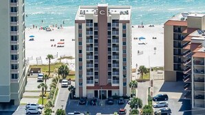 Ein Hochhaus-Hotel mit einem zentralen Atrium, Blick auf den Strand und einem Parkplatz mit mehreren Autos.