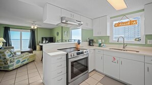 Eine moderne Küche mit weißen Schränken, einem eingebauten Ofen und einem großen Fenster mit Strandanzeige.
