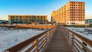 A wooden boardwalk leading to a hotel with multiple floors and balconies. - Plantation 6407-Beachfront Condo w/Heated Pool! (Gulf Shores)