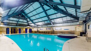 An indoor swimming pool with a high ceiling and skylights, surrounded by lounge areas and doors. - Plantation 6407-Beachfront Condo w/Heated Pool! (Gulf Shores)