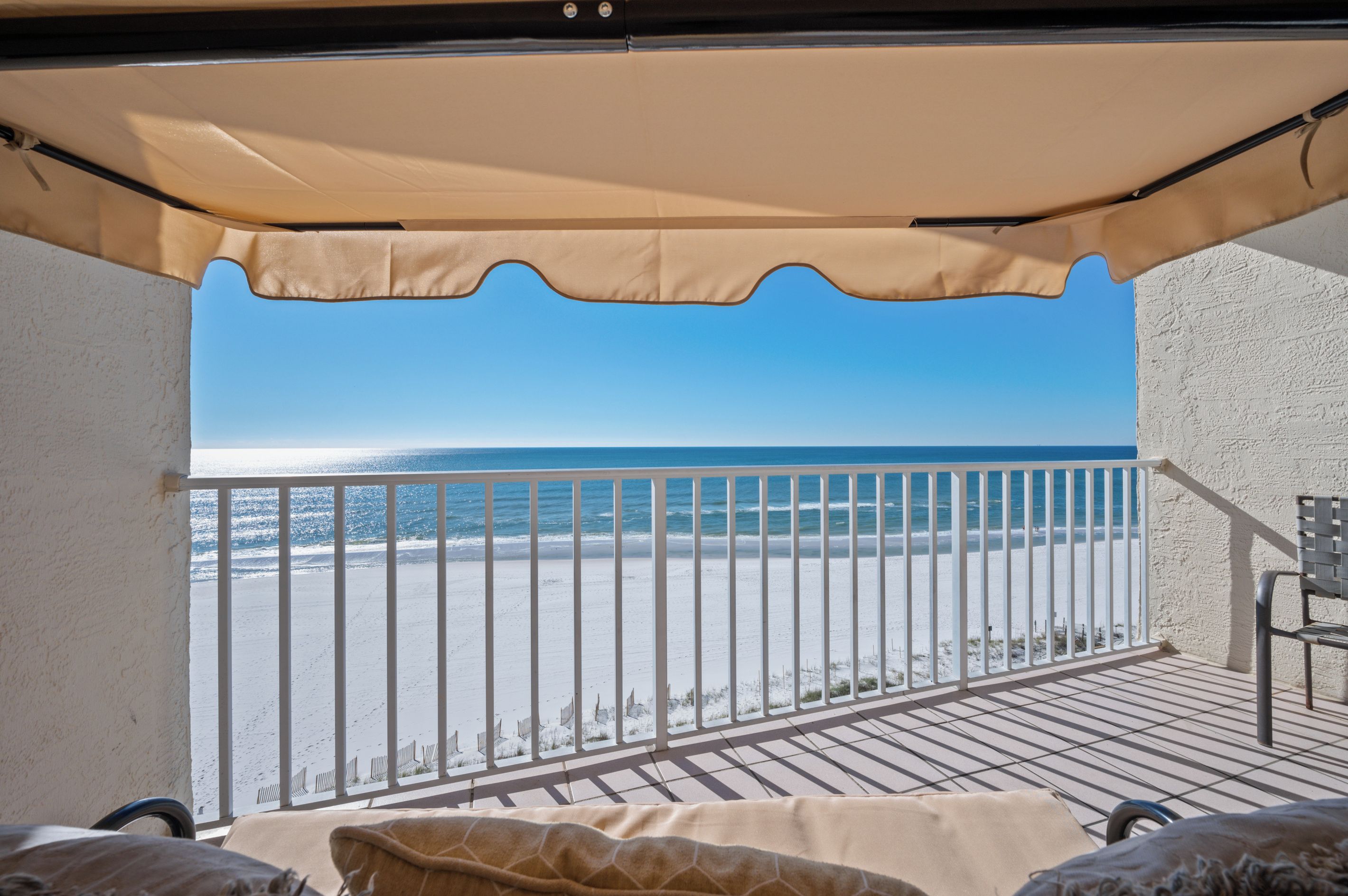A balcony with a view of the beach and ocean.