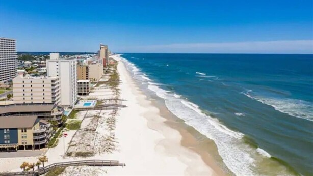 Un hotel costero con vista a la playa, varias edificaciones y cielo despejado.