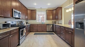 A modern kitchen with dark wood cabinets, stainless steel appliances, and a large window. - Spacious 3BR Home near Tysons and Metro | Private Yard (Falls Church)