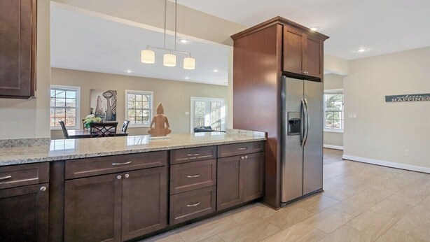 A spacious kitchen with dark wooden cabinets, a stainless steel refrigerator, and a marble countertop. - Spacious 3BR Home near Tysons and Metro | Private Yard (Falls Church)