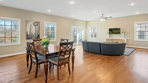 A spacious living room with a wooden dining table, chairs, and a gray sofa. - Spacious 3BR Home near Tysons and Metro | Private Yard (Falls Church)