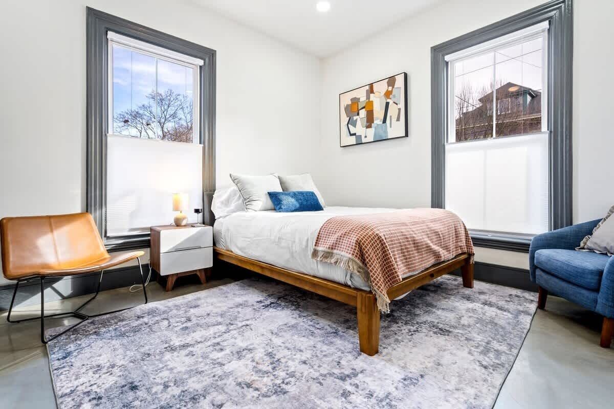 Een slaapkamer met een bed, nachtkastje, stoel en een bank.
