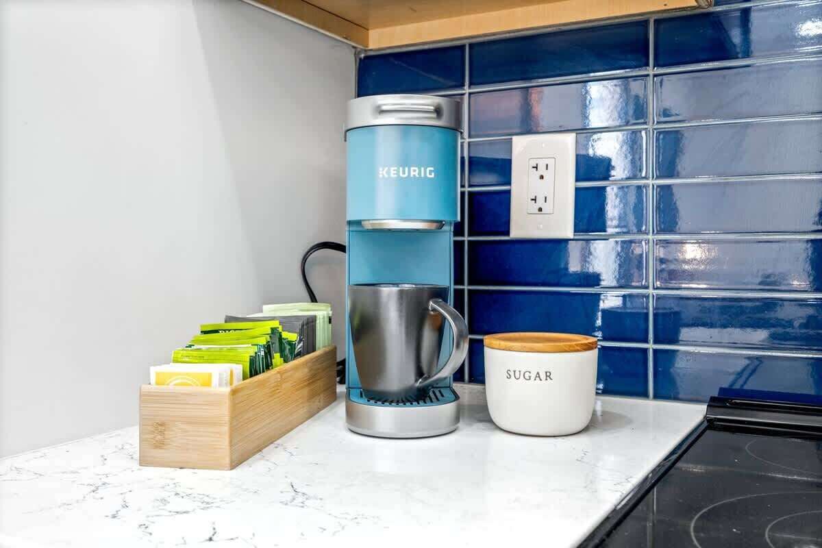 A coffee maker, a mug, and a box of coffee pods on a kitchen counter.