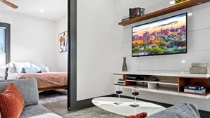 Un salon moderne avec un téléviseur à écran plat, un canapé, une table basse et un lit.