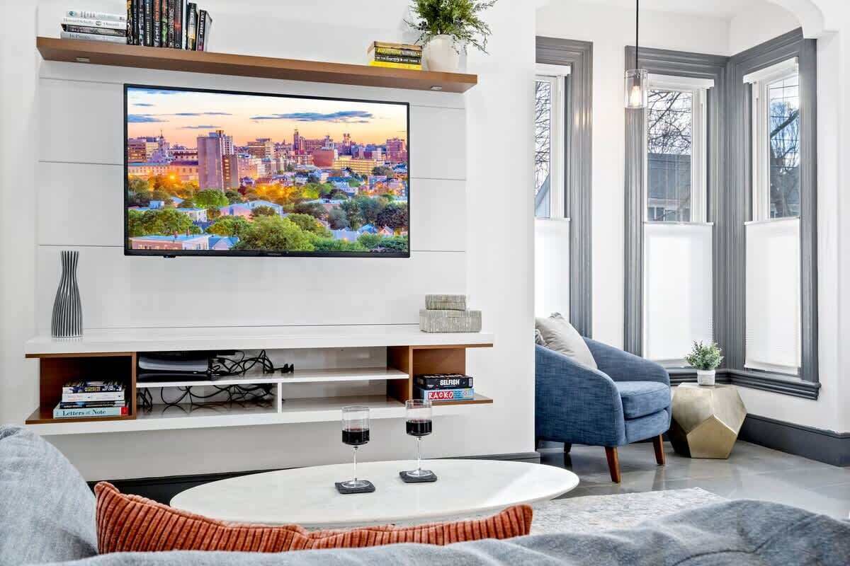 A modern living room with a flat-screen TV mounted on the wall, a coffee table, a sofa, and a blue armchair.