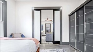 Une chambre à coucher moderne avec un lit, une grande fenêtre et une armoire.