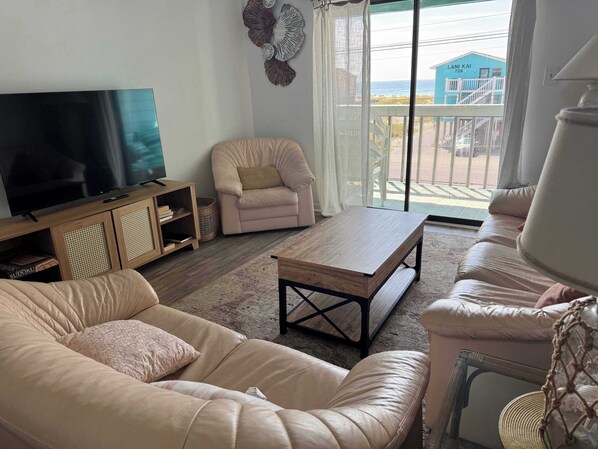 Una sala de estar con un sofá, una mesa de centro, un televisor y una silla.