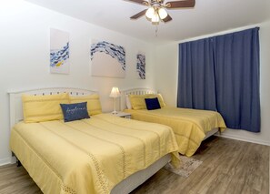 Ein Schlafzimmer mit zwei Betten, einem Deckenventilator und Bildern an den Wänden.