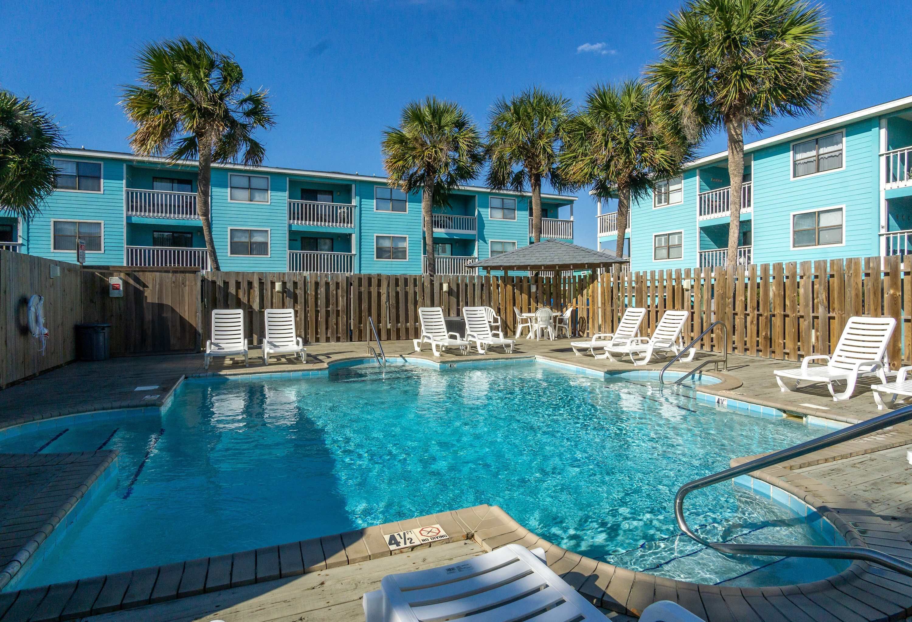 A swimming pool with lounge chairs and a wooden fence.