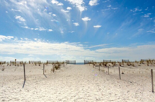 A sandy beach with a wooden fence and a clear sky.