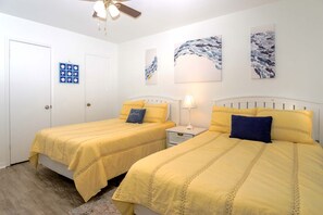Ein Schlafzimmer mit zwei Betten, einem Deckenventilator und Kunstwerken an den Wänden.