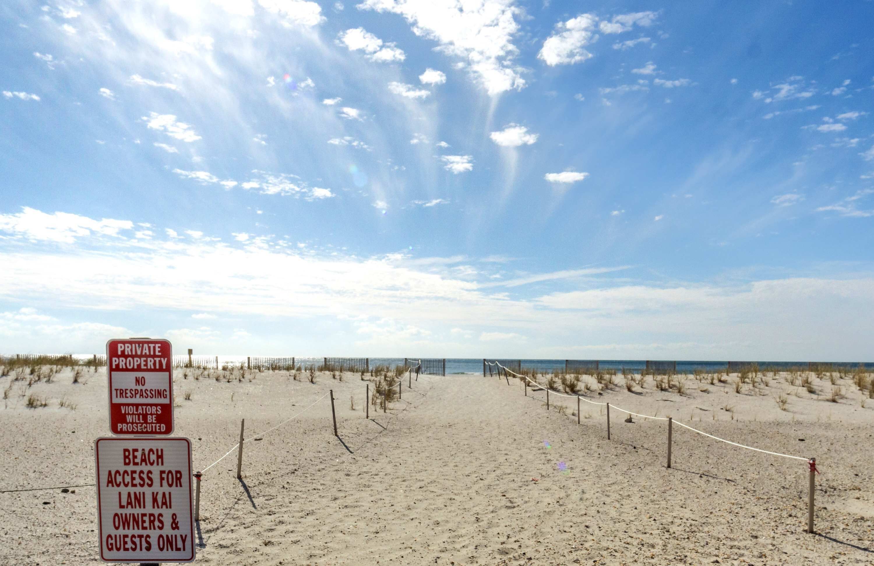 Een strand met borden die aangeven dat het privé-eigendom is en de toegang beperkt is tot eigenaren en gasten van Lani Kai.
