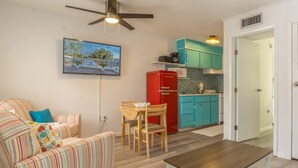 Ein Wohnzimmer mit einem gestreiften Sofa, einem Holztisch und einem Deckenventilator.