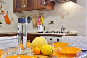 A kitchen with a water bottle, a lemon, an orange, and orange plates on a table. - GuestHost - Cozy apartment that can accommodate up to 6 people, located in an independent villa with garden. The apartment is 900 meters from the Circumvesuviana for Naples-Pompei-Sorrento, perfect for traveling in the area and reaching all points of int (San Giorgio a Cremano)