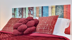 A bed with a red blanket and pillows, a wooden wall with peeling paint, and a white pillow with a geometric pattern. - GuestHost - Cozy apartment that can accommodate up to 6 people, located in an independent villa with garden. The apartment is 900 meters from the Circumvesuviana for Naples-Pompei-Sorrento, perfect for traveling in the area and reaching all points of int (San Giorgio a Cremano)