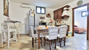 A compact kitchen with a dining table, chairs, a refrigerator, microwave, and a small window. - GuestHost - Cozy apartment that can accommodate up to 6 people, located in an independent villa with garden. The apartment is 900 meters from the Circumvesuviana for Naples-Pompei-Sorrento, perfect for traveling in the area and reaching all points of int (San Giorgio a Cremano)