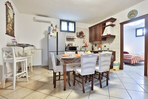 Eine kleine Küche mit Esstisch, Stühlen, Kühlschrank, Mikrowelle und einem kleinen Fenster.