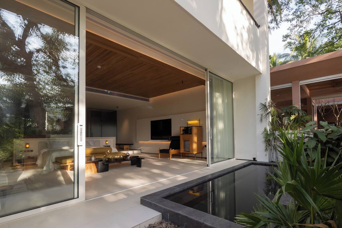 A modern interior with a glass door leading to a balcony, a wooden ceiling, and a seating area with a sofa and coffee table.