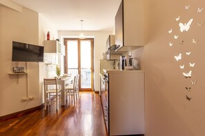 Une cuisine moderne avec un coin repas, un téléviseur et une porte donnant sur un balcon.