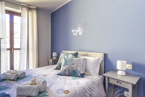 A bedroom with a bed, pillows, a bedside table with a lamp, and a wall decoration.