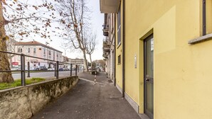 A street with a yellow building, a sidewalk, and a tree.