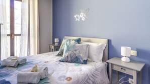 A bedroom with a bed, pillows, a bedside table with a lamp, and a wall decoration.