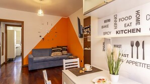 A modern living room with a sofa, a dining table with a cup and snacks, and a wall with food-related words.