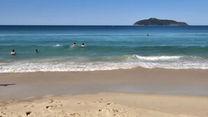 Une plage à l’eau claire, un rivage sablonneux et une île qui se dessine à l’horizon.